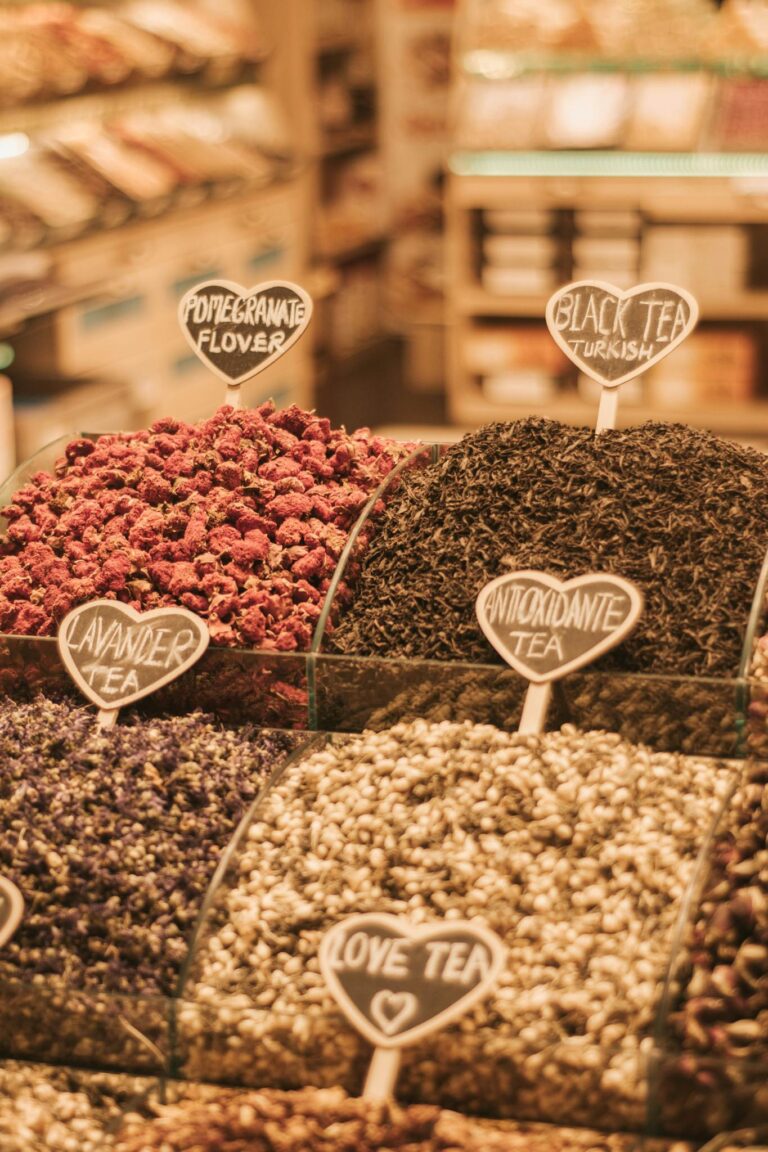 A variety of loose herbal teas on display in a market, featuring pomegranate flower, black tea, and more.